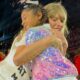 Exclusive: Taylor Swift trots up to a young fan belting out her song lyrics. After giving the girl a sweet hug, Swift hands her the coveted 22 trilby, causing the young fan to burst into happy tears...